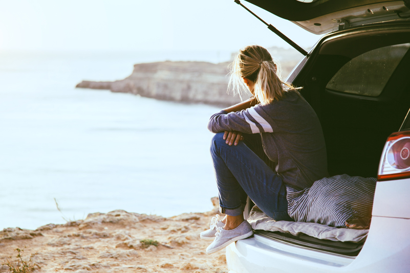 A woman admires a view after buying a car thanks to her good credit score.